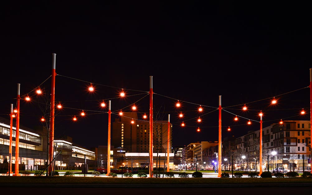 The catenary lighting installation at the D Street Corridor in Boston, Massachusetts, helps draw attention to the pedestrian connection between the Boston Convention and Exhibition Center (BCEC) and the surrounding neighborhood and businesses.